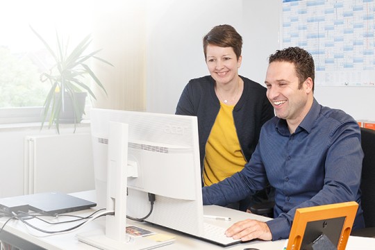 Im Büro schauen sich eine Frau und ein Mann Informationen am Computer an.
